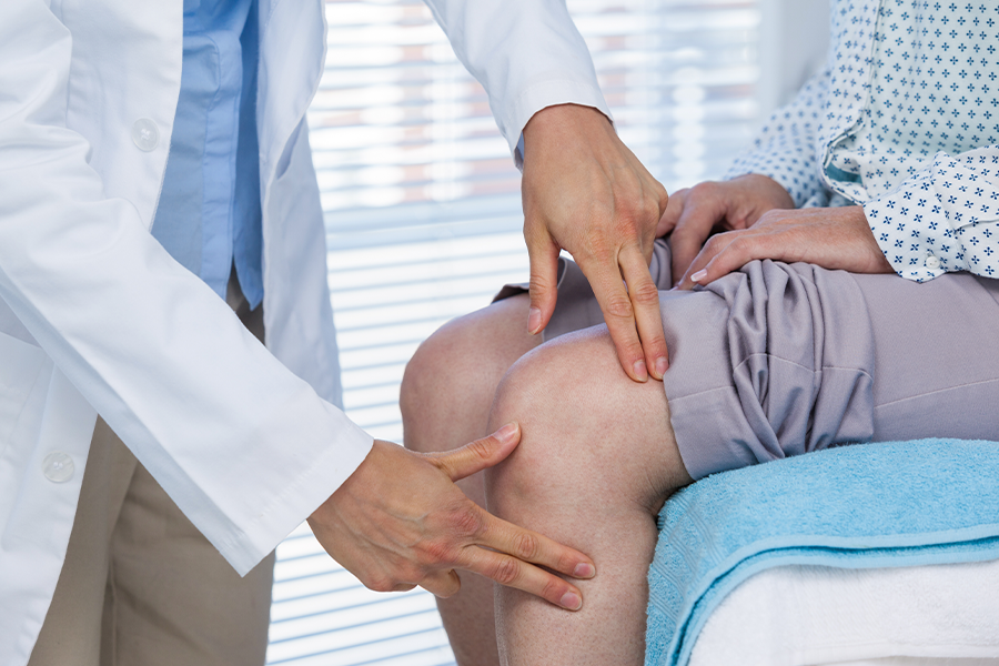 Doctor examines knee to determine if it causes shoulder pain in patient