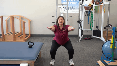 Physical therapist demonstrates a standard squat, a great pregnancy exercise for pelvic health.
